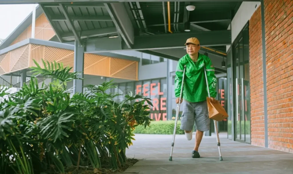 A man in crutches walking down a sidewalk