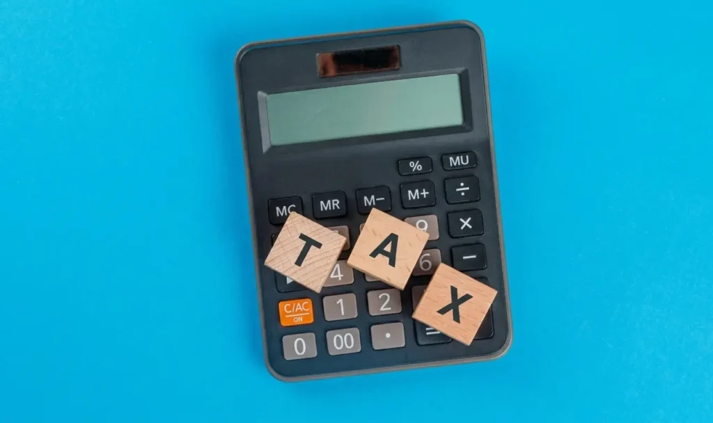 Block tiles representing tax on a calculator with blue background