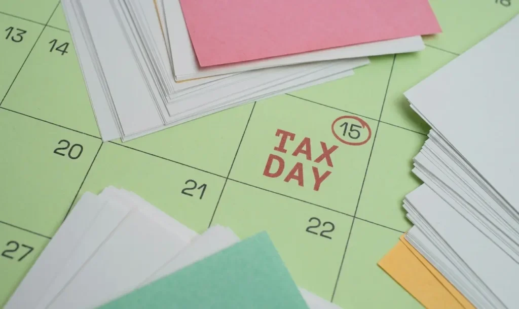 Tax day marked in red on a green calendar with papers lying around